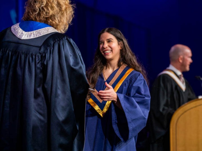 Graduate smiles as they receive certificate