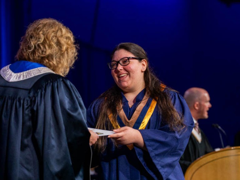 Graduate smiles as they receive certificate