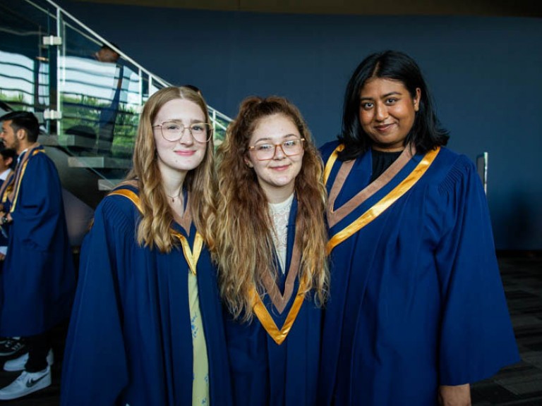 Three graduates pose for photo