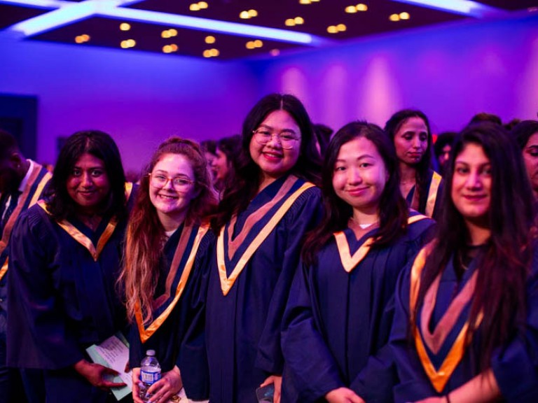 Graduates in ceremony audience smile at camera