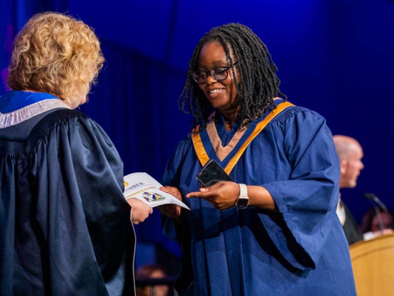 Graduate smiles as they receive certificate