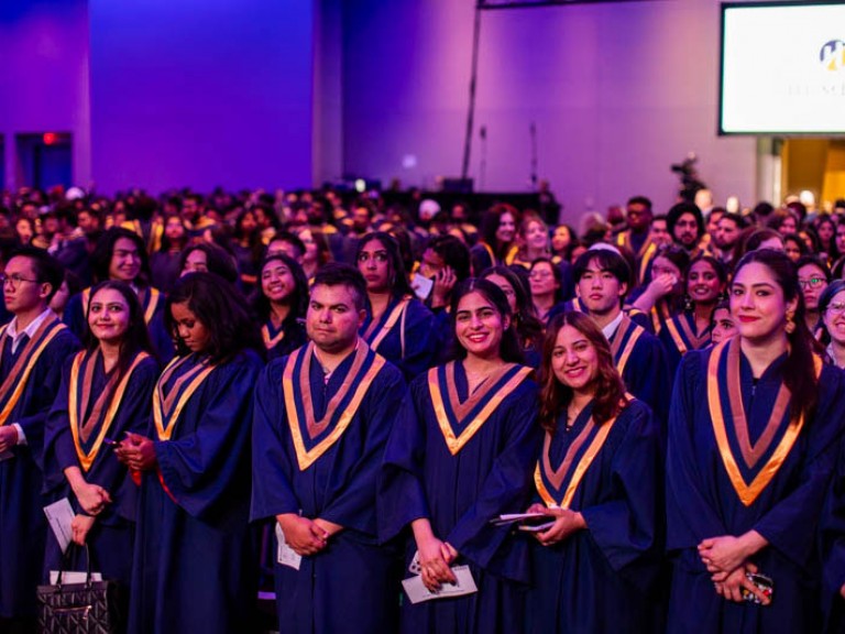 Graduates standing in the ceremony audience