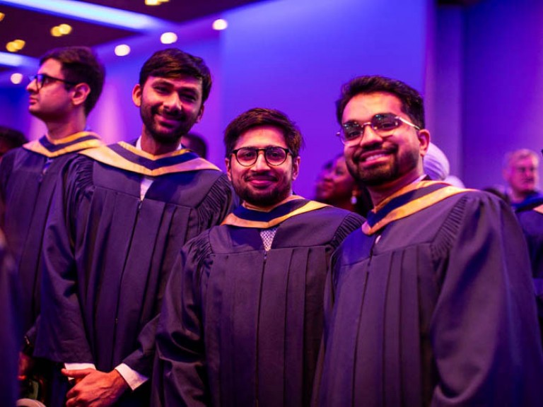 Graduates in the ceremony hall smile at camera