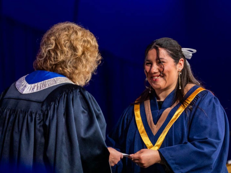 Graduate smiles as they receive certificate