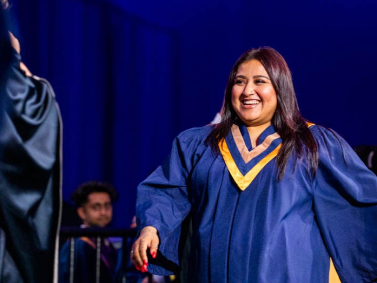 Graduate smiles as they cross stage