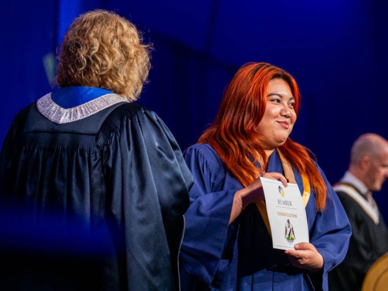 Graduate looks towards audience with their certificate