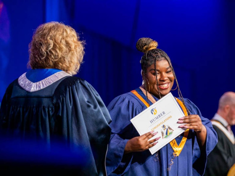 Graduate smiles with their certificate on stage