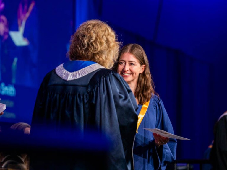 Graduate smiles as they receive certificate