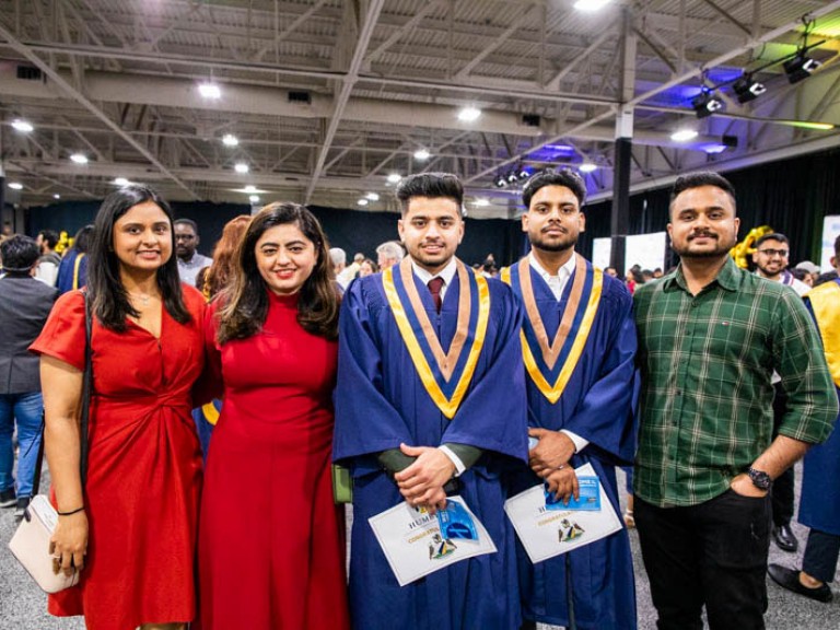Two graduates take photo with three guests
