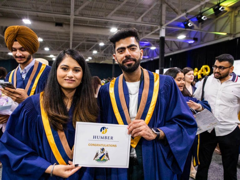 Two graduates pose with certificate held between them