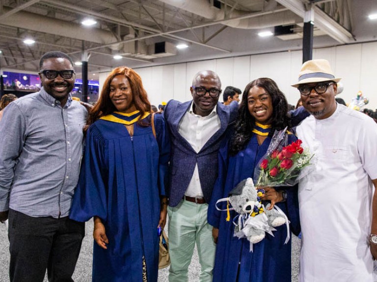 Two graduates take photo with three family members