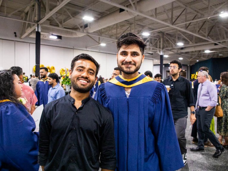 Graduate stands beside guest for photo