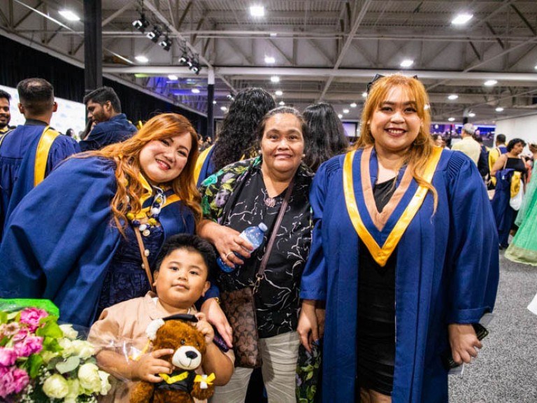Two graduates pose with two family members