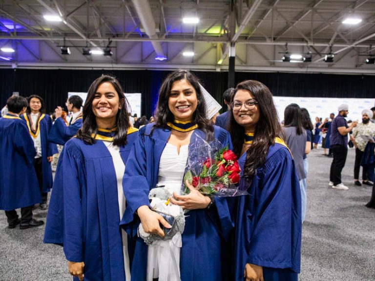 Three graduates stand together for photo