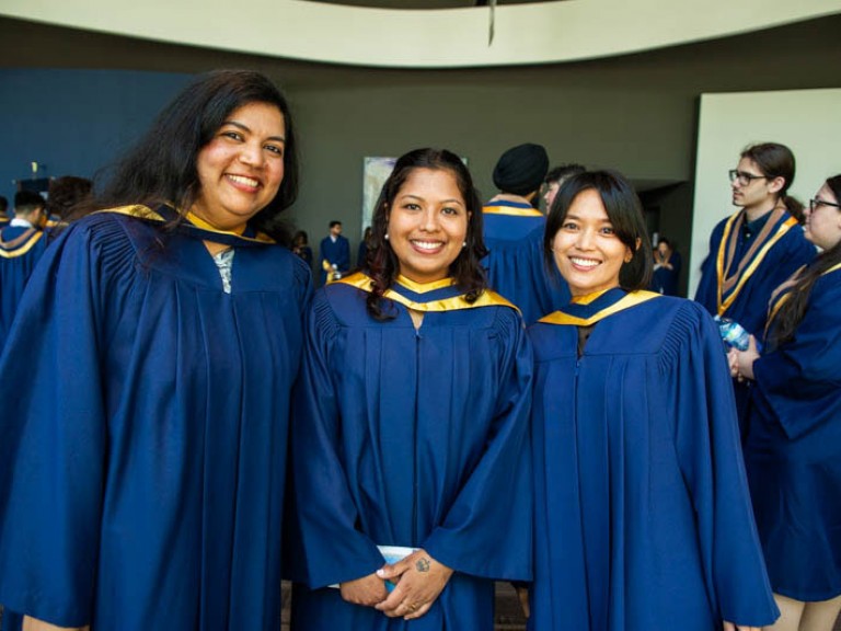 Three graduates smile for camera