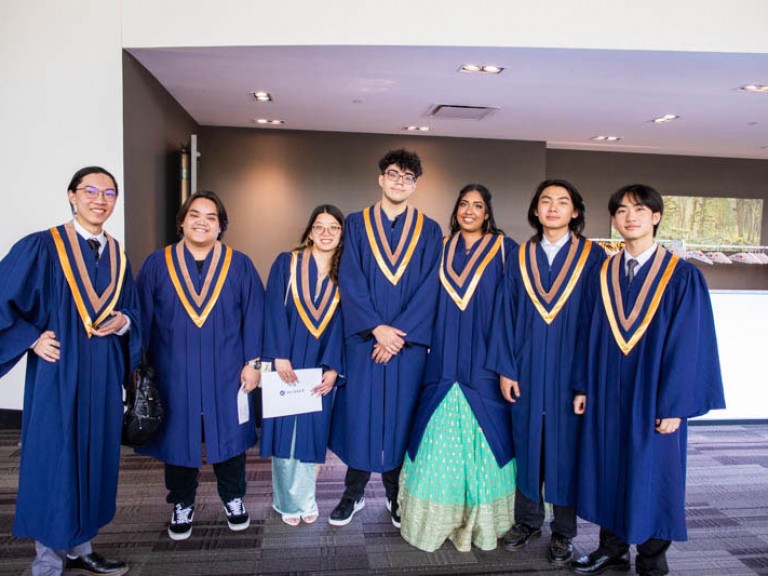 Seven graduates stand together for photo