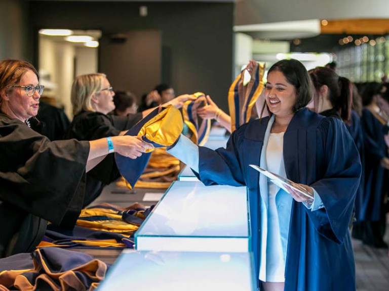 Graduate receives their sash over a counter
