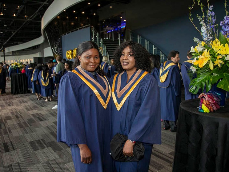 Two graduates pose for photo in the reception area