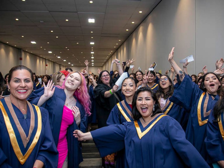 Graduates smile and raise arms