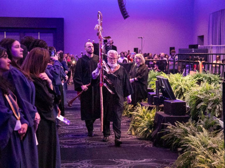 Humber faculty members carrying ceremonial Indigenous staffs proceed through hall