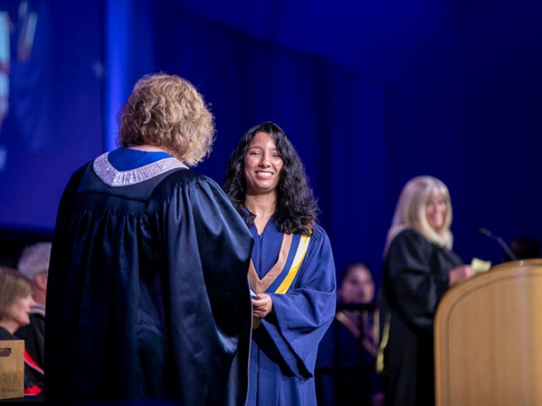 Graduate smiles as they receive certificate