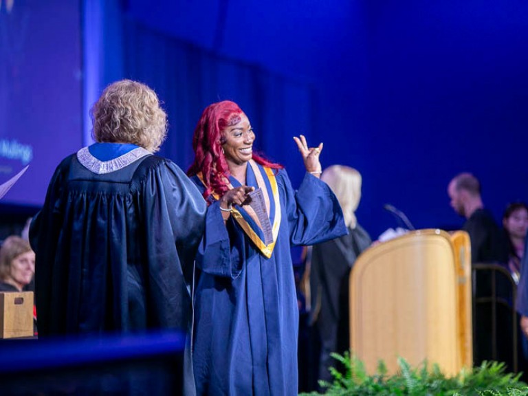 Graduate holds up peace sign on stage