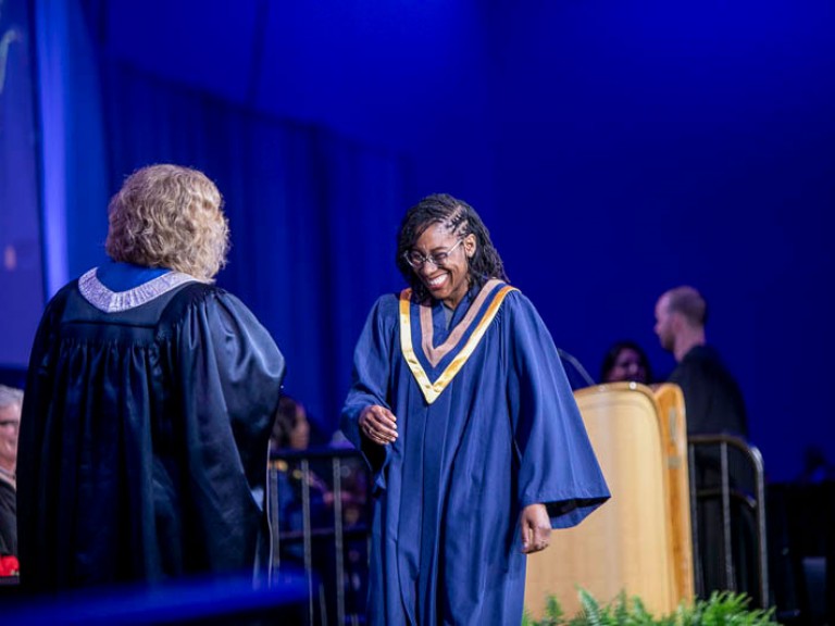 Graduate smiles as they cross the stage