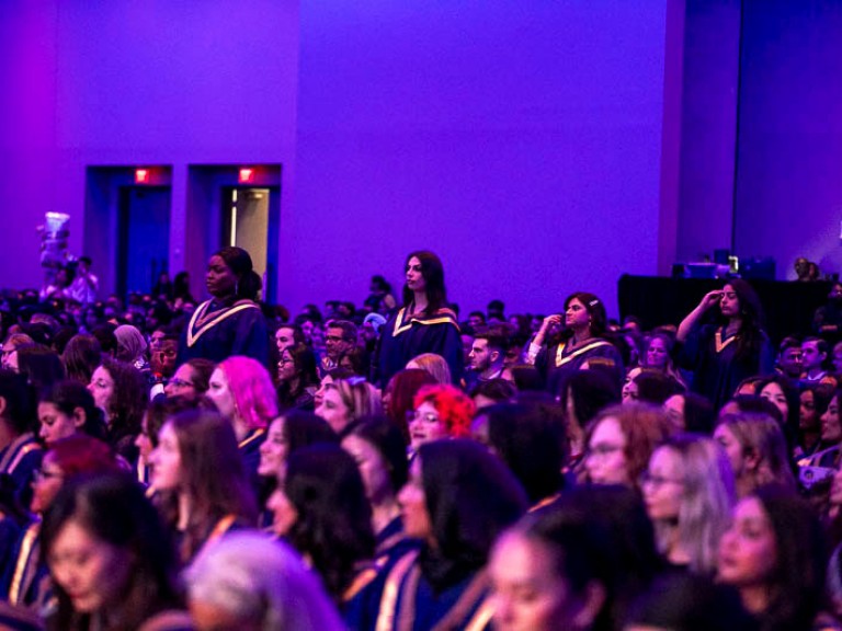 Four graduates standing in the audience