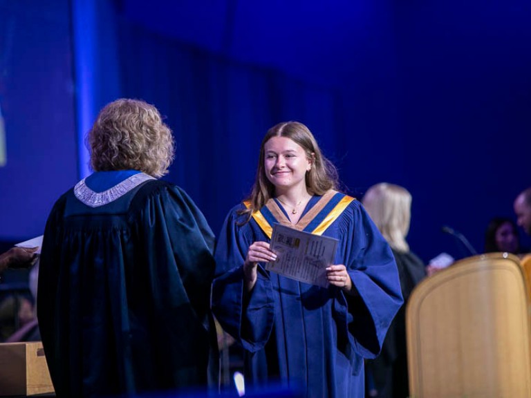 Graduate smiles as they receive certificate