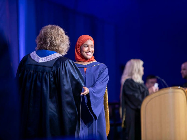 Graduate smiles as they receive certificate