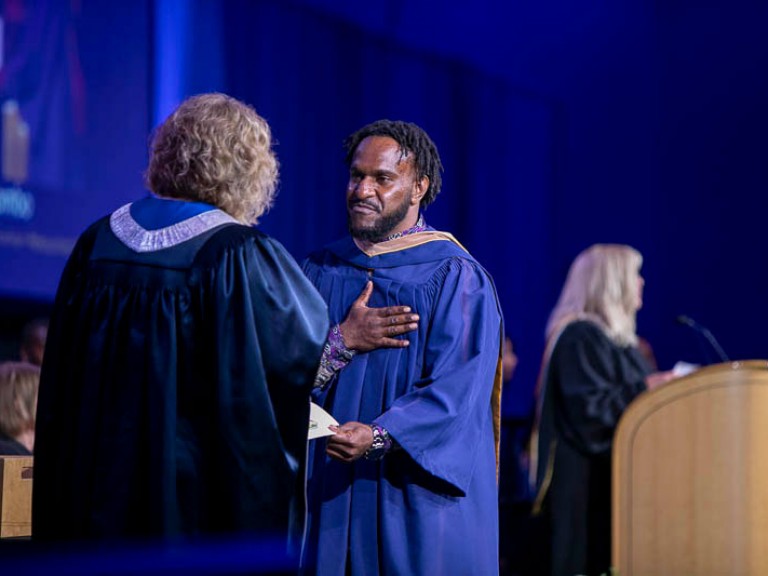 Graduate receives certificate with a hand on his chest