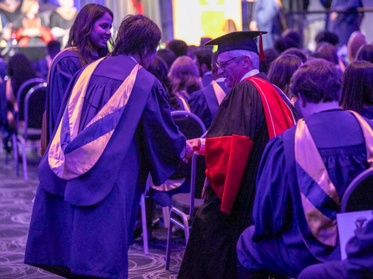 Graduate shakes hand of Humber faculty member in audience