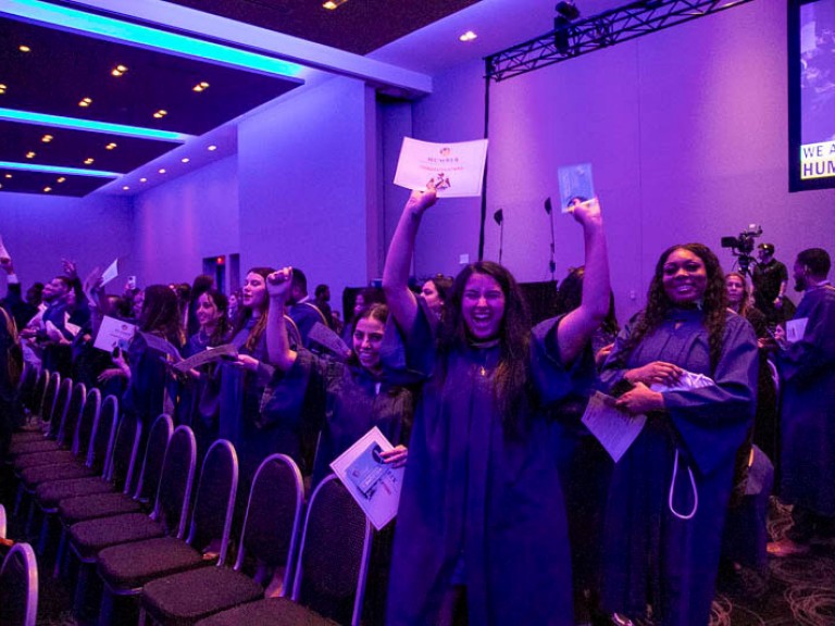 Graduate raises arms in celebration in audience