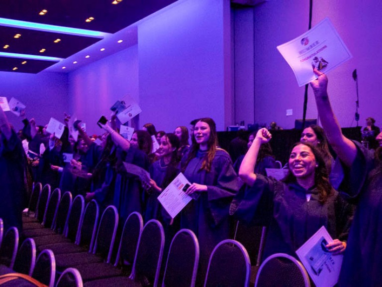 Graduates raise their arms in celebration