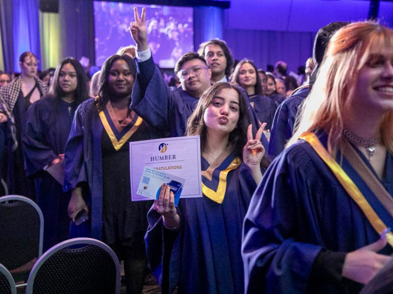 Graduates make peace signs as they leave ceremony hall