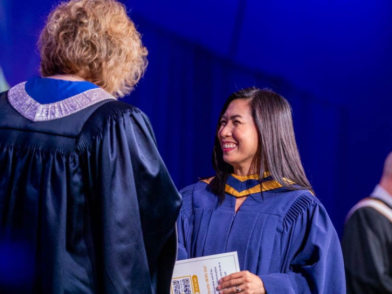 Graduate smiles as they receive certificate