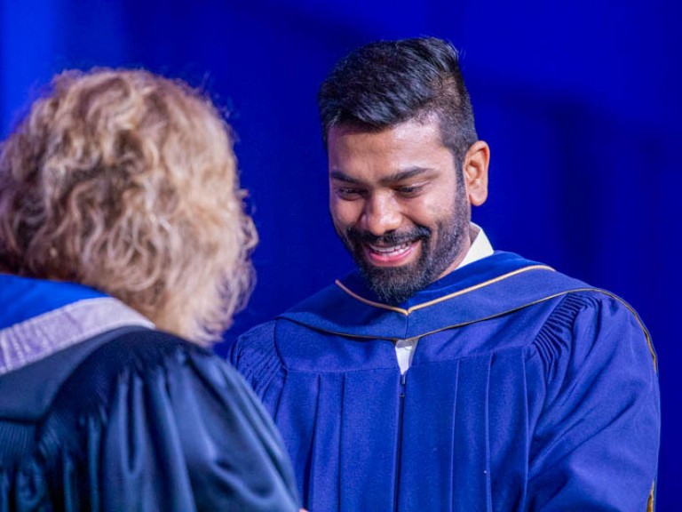 Graduate smiling as they receive their credential