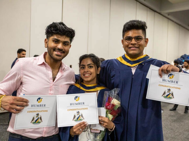 Three graduates hold their certificates