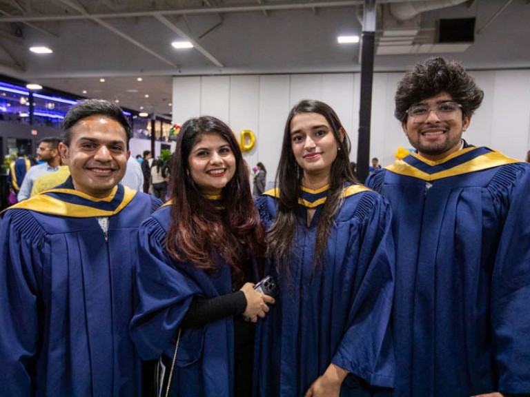 Four graduates pose for camera