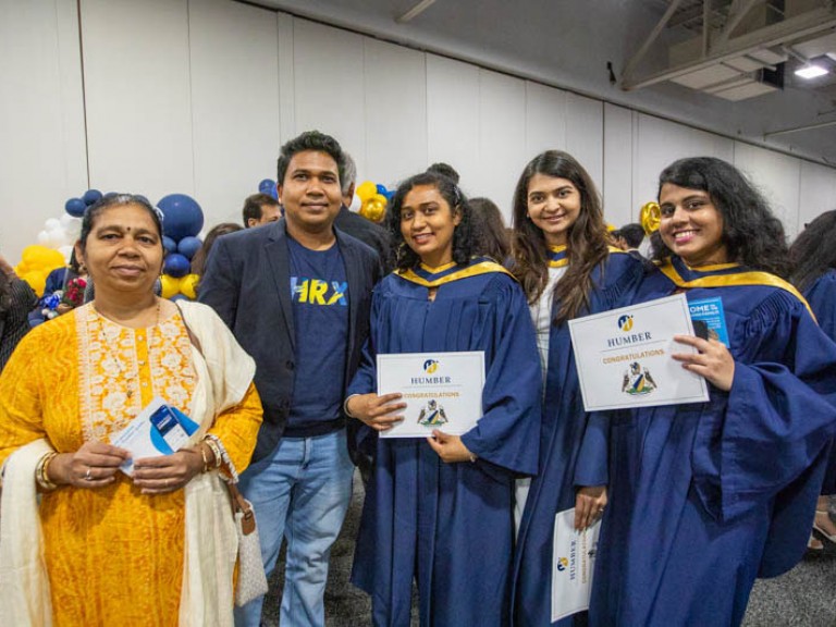 Three graduates and two guests take photo together