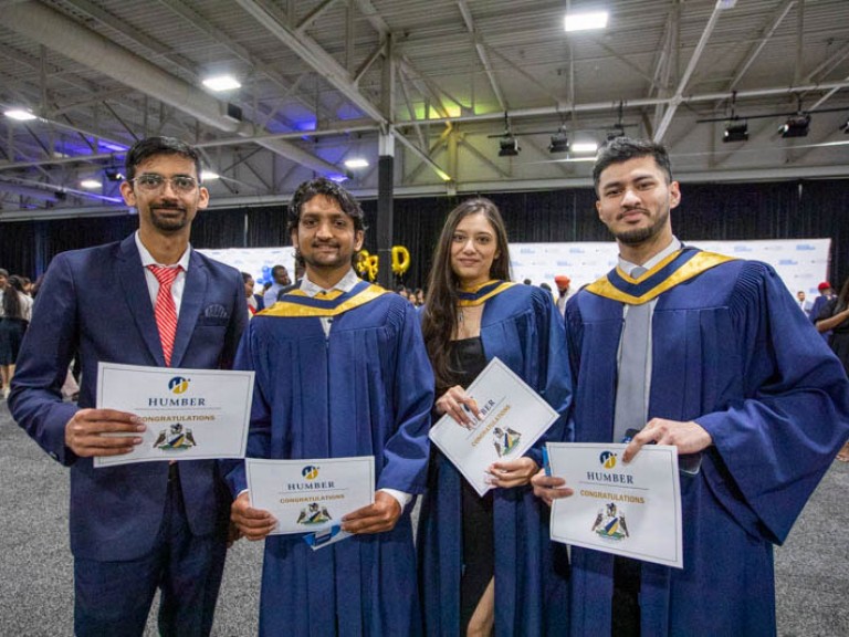 Four graduates hold their certificates