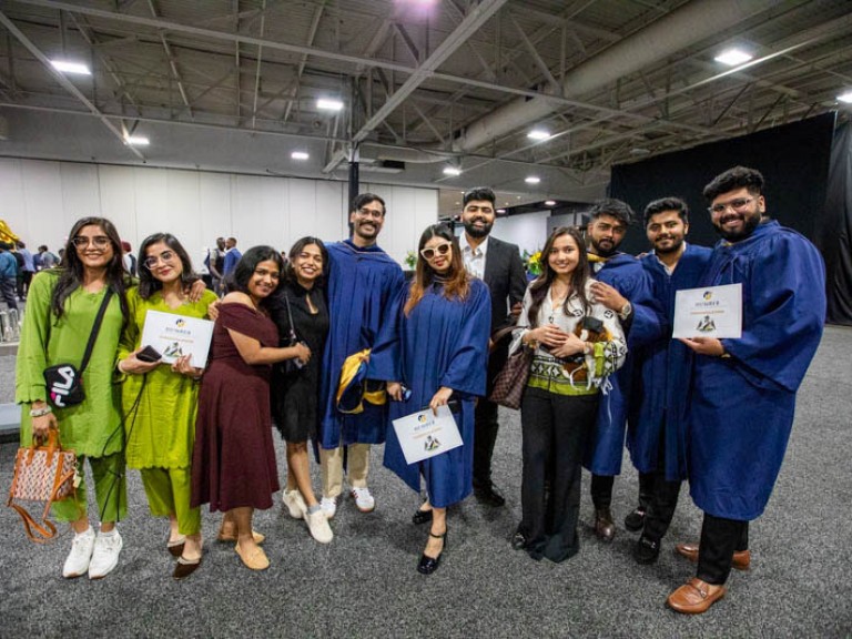 Eleven people stand in line for photo together