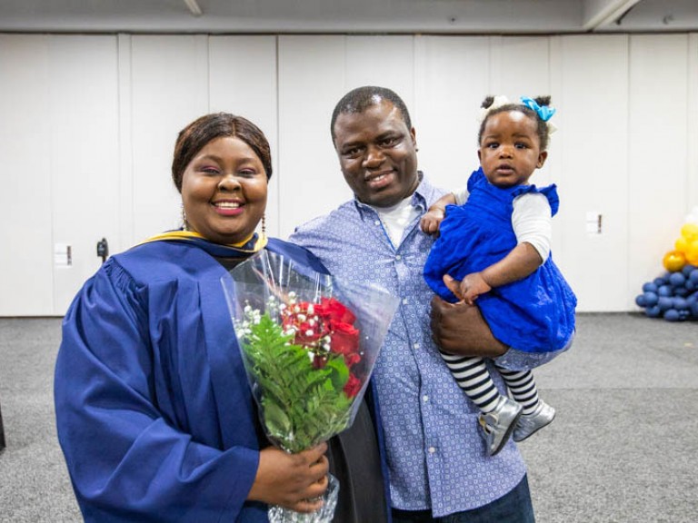 Graduate poses with guest holding a baby