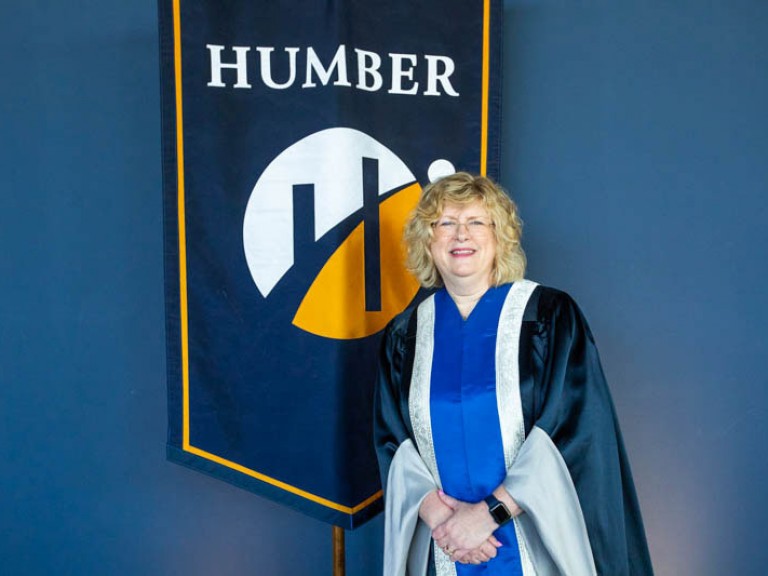 Humber president Ann Marie Vaughan in front of Humber flag