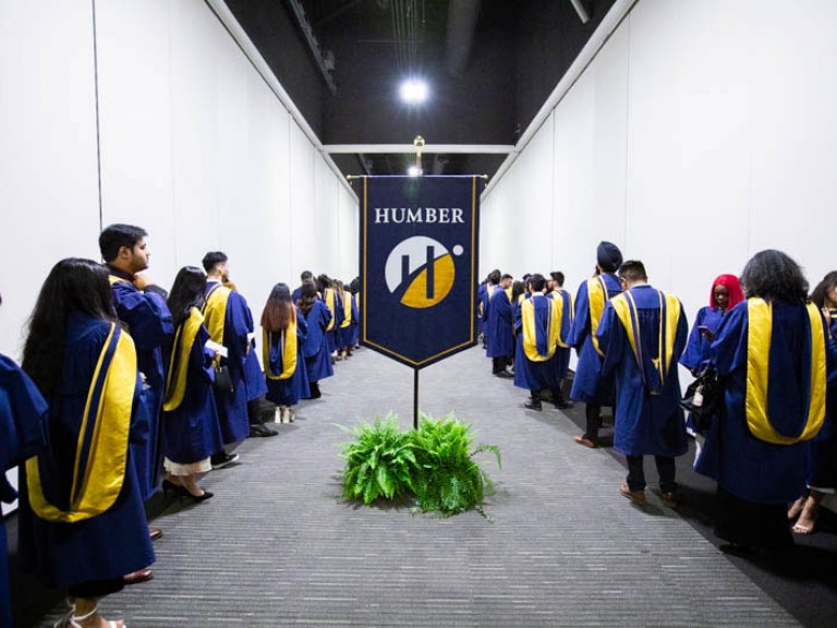 Two rows of Humber graduates in hallway