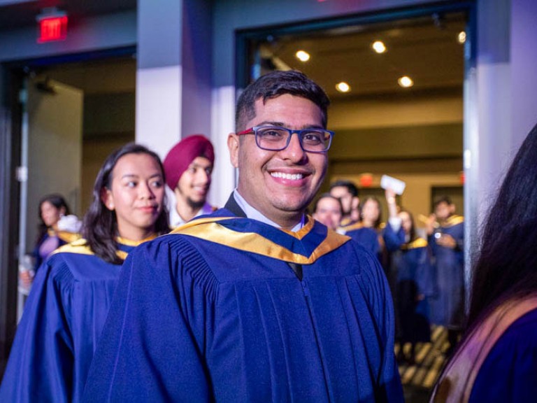 Graduate smiles as they proceed into hall