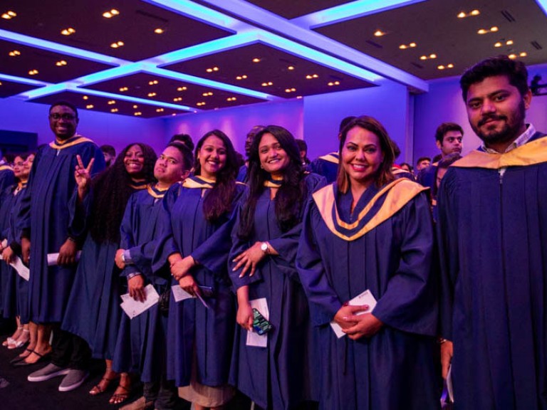 Row of graduates look at camera