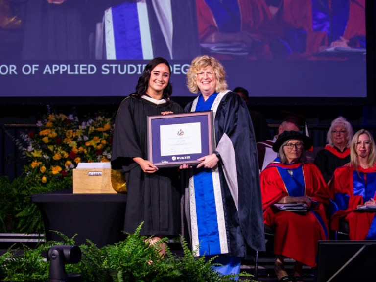Honorary degree recipient Kaetlyn Osmond holding framed award with Humber president Ann Marie Vaughan