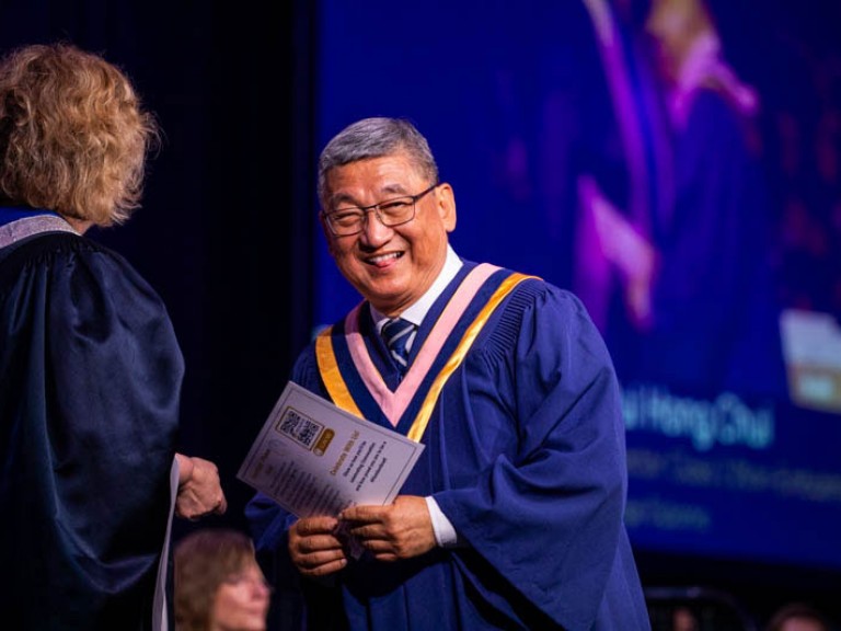 Graduate on stage smiles at camera