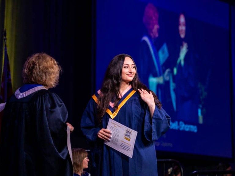 Graduate waves at audience on stage